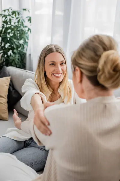 Two charming sisters in pastel cardigans looking at each other, hand on shoulder, family bonding — Stock Photo