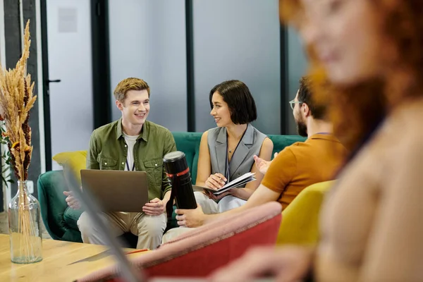 Sonriente gerente con el ordenador portátil hablando con el equipo de negocios en la moderna oficina de coworking, borrosa primer plano - foto de stock