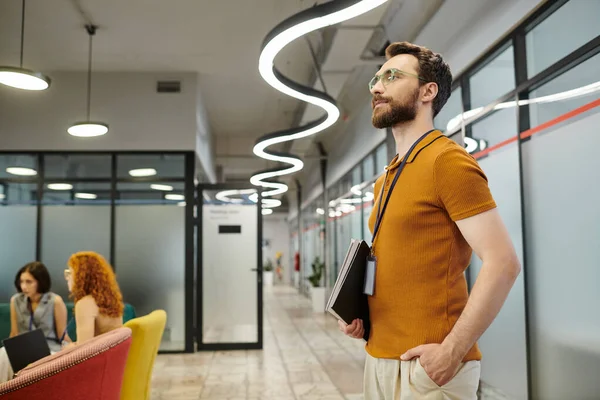 Confident bearded business standing with documents, businesswomen talking on blurred background — Stock Photo