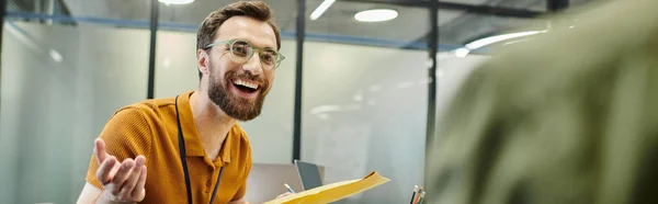 Радісний бородатий підприємець з конвертом розмовляє з розмитим діловим партнером в офісі, банер — стокове фото