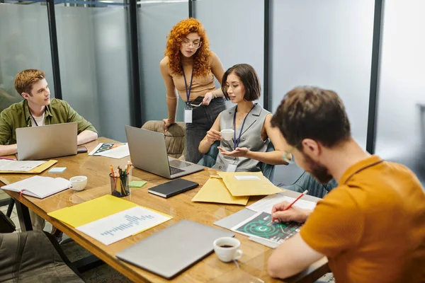 Coworking office, laptops, documents, redhead entrepreneur near creative team working on startup — Stock Photo