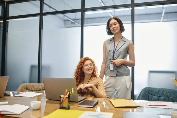 Professioneller Kopfschuss junger Geschäftsfrauen, die am Arbeitsplatz im Büro in die Kamera neben dem Laptop schauen — Stockfoto