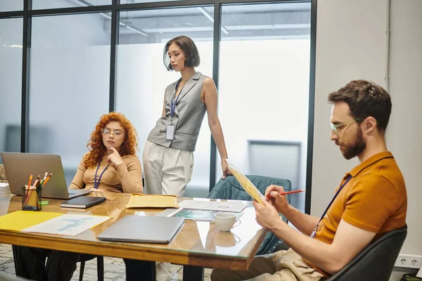 Thoughtful businesswomen looking at laptop near bearded colleague with envelope, startup planning — Stock Photo