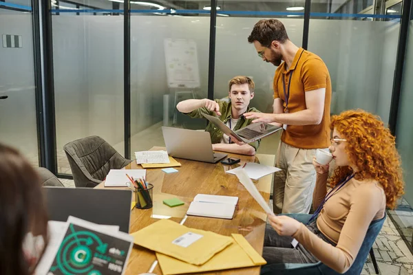 Менеджер указывая на ноутбук рядом с командой ведущих и коллег в конференц-зале, стартап, мозговой штурм — стоковое фото