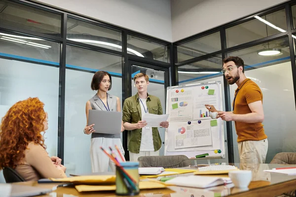 Meeting room, startup, excited bearded businessman talking to team near flip chart with graphs — Stock Photo