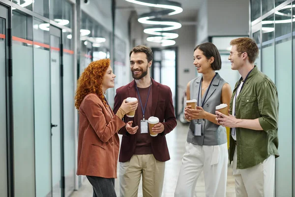 Equipe de negócios feliz com bebidas takeaway falando durante coffee break no escritório contemporâneo — Fotografia de Stock