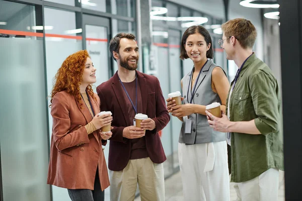 Joyful and creative business team with disposable cups talking during coffee break in office — Stock Photo