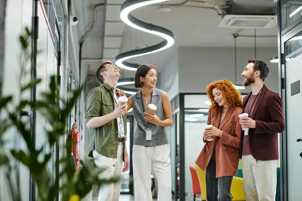 Coffee break in coworking office, optimistic managers talking and holding takeaway drinks — Stock Photo