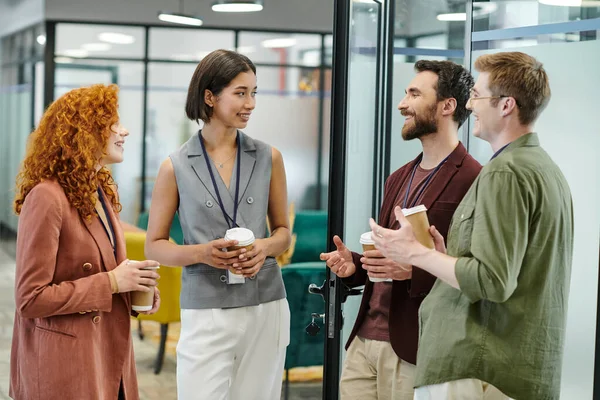 Conversation of happy business colleagues holding takeaway drinks during coffee break in office — Stock Photo