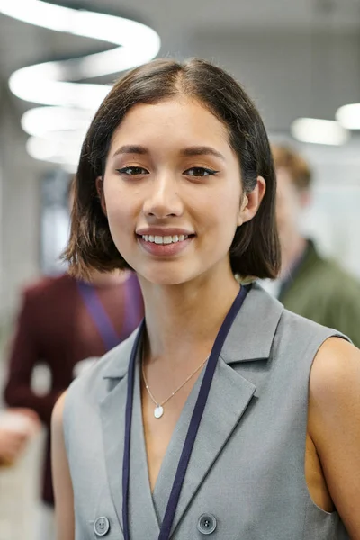 Portrait of joyful brunette businesswoman looking at camera in contemporary office — Stock Photo
