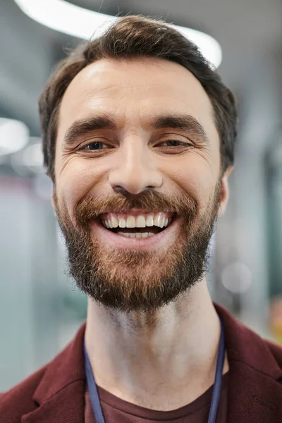 Portrait d'un homme d'affaires barbu excité avec un sourire radieux regardant la caméra dans un bureau contemporain — Photo de stock