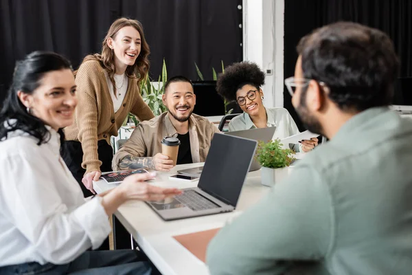 Happy interracial business team looking at colleague on blurred foreground, brainstorming — Stock Photo