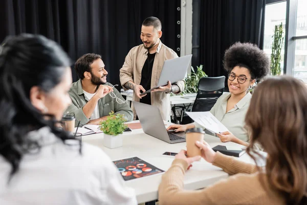 Happy interracial business team talking to team leader on blurred foreground, brainstorming — Stock Photo