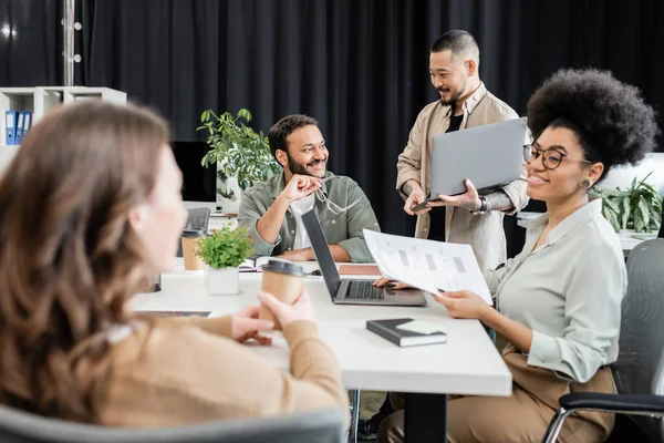Happy african american team lead holding documents and discussing project with female colleague — Stock Photo