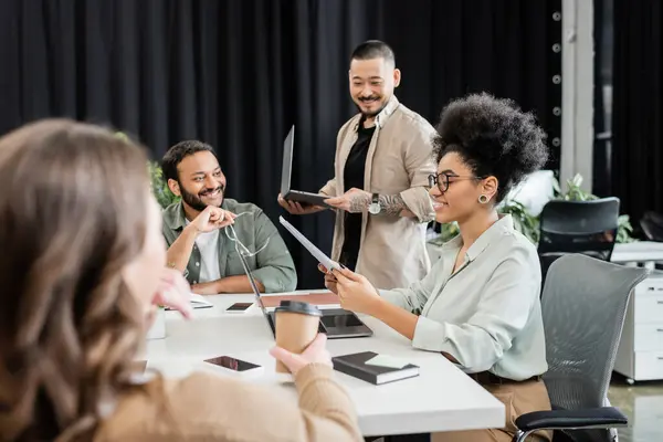 Happy african american team leader holding documents and discussing project with colleagues — Stock Photo