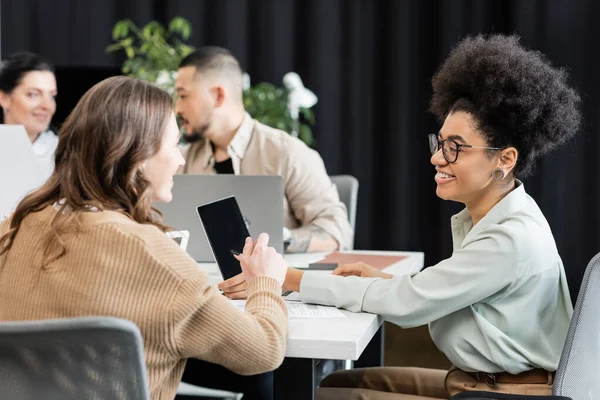 Happy interracial female colleagues talking in modern coworking, project planning and collaboration — Stock Photo