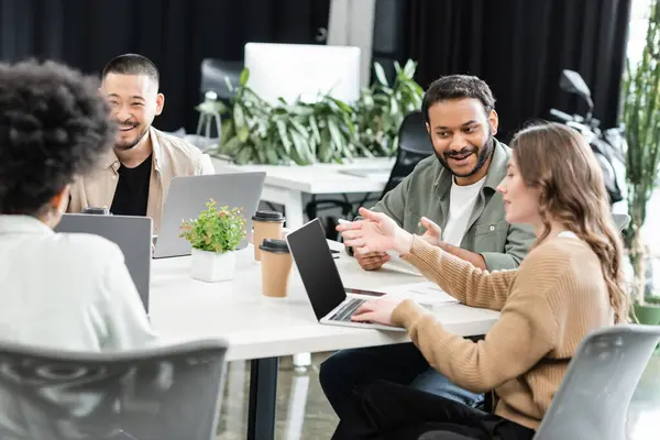 Cheerful interracial colleagues using laptops and planning project together in modern coworking — Stock Photo