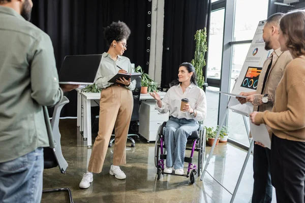 Concept d'inclusion, femme handicapée en fauteuil roulant partageant des idées avec des hommes d'affaires interracial — Photo de stock