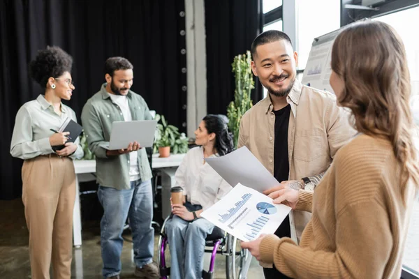 Diversity and inclusion, happy asian man communicating with female colleague near disabled woman — Stock Photo