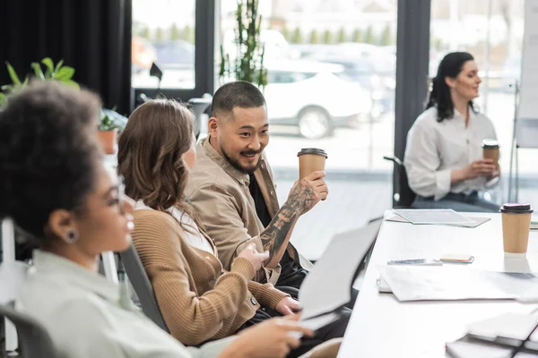 Joyful asian businessman chatting with female colleague in modern coworking, startup ideas — Stock Photo