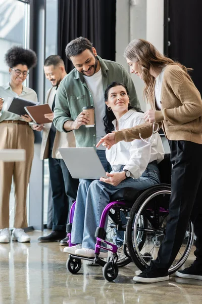 Disabled woman in wheelchair discussing startup project with happy interracial team in coworking — Stock Photo