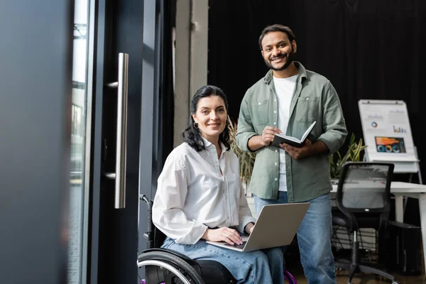 Three interracial businesswomen, disabled woman in wheelchair working with female team in office — Stock Photo