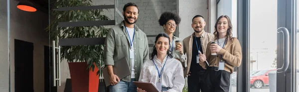 Diverso equipo de startups mirando a la cámara y posando en la oficina, pancarta de gente de negocios interracial - foto de stock
