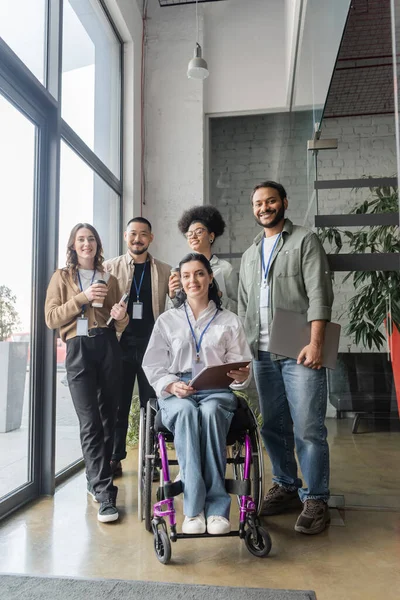 Group shot of diverse startup team looking at camera in office, wheelchair user, inclusion concept — Stock Photo