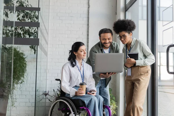 Груповий знімок різних бізнесменів, жінка з обмеженими можливостями на інвалідному візку, дивлячись на ноутбук з колегами — стокове фото