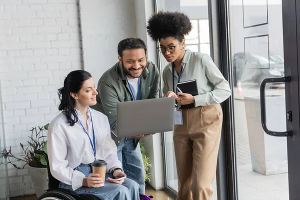 Group happy diverse business people, disabled woman on wheelchair looking at laptop with coworkers — Stock Photo