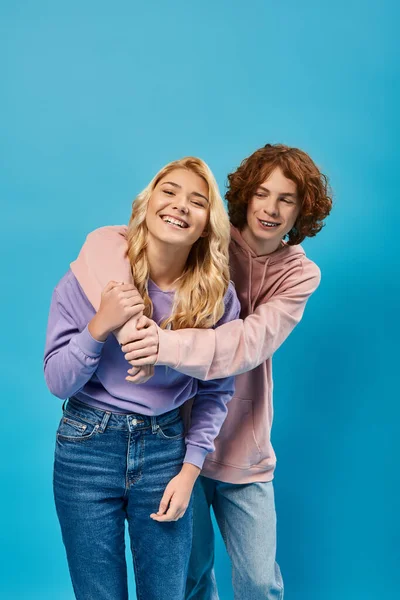 Pelirroja adolescente chico abrazando riendo novia en azul, amistad de los adolescentes con estilo - foto de stock