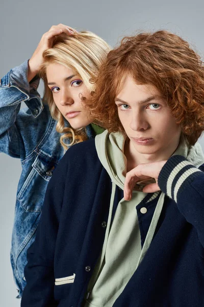 Amici adolescenti sicuri in abiti casual alla moda guardando la fotocamera su grigio, moda giovanile — Foto stock