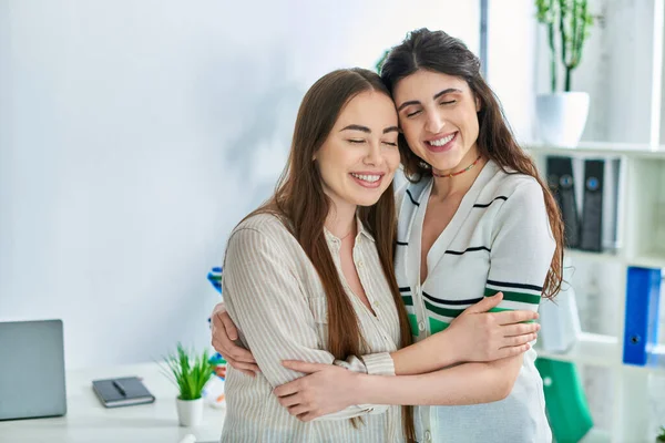 Joyeux couple lesbien souriant avec les yeux fermés et étreignant chaudement, concept de fécondation in vitro — Photo de stock