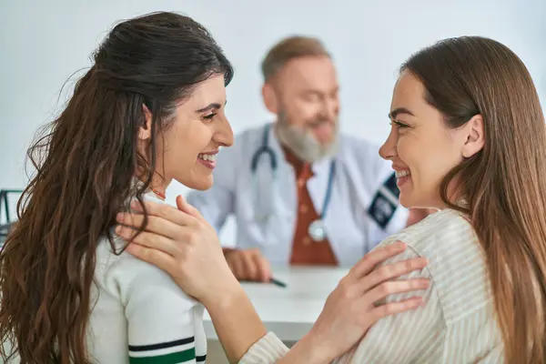 Casal lésbico sorrindo alegremente um para o outro depois que o médico lhes deu ultra-som, conceito ivf — Fotografia de Stock