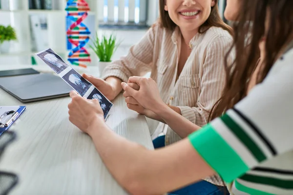 Joyeux couple lesbien souriant joyeusement et tenant échographie de leur bébé, concept ivf — Photo de stock