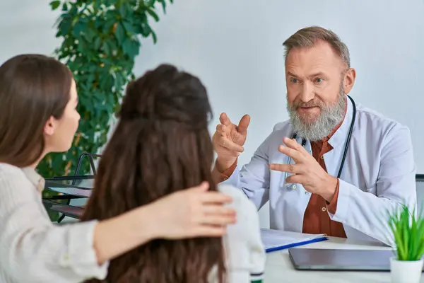 Beautiful couple talking to grey bearded gynecologist at his office, in vitro fertilization concept — Stock Photo