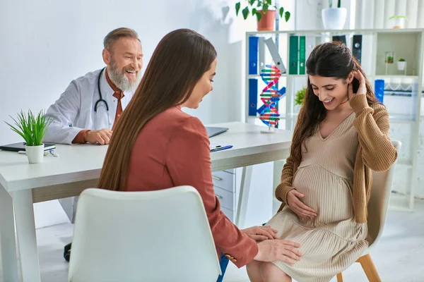 Jeune couple lgbt avec la main sur le ventre enceinte ayant rendez-vous chez le médecin, fécondation in vitro — Photo de stock