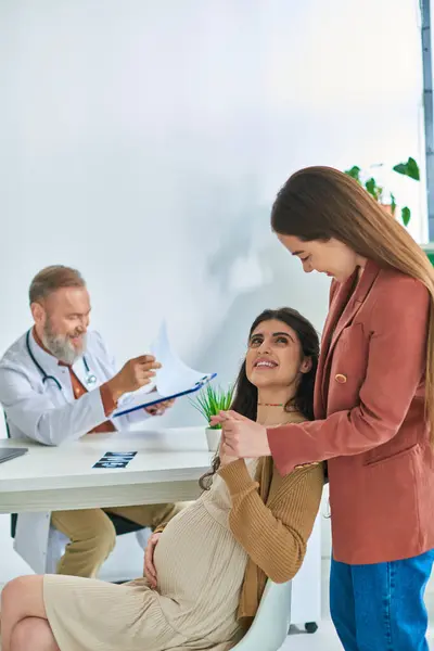 Young expectant lesbian couple having doctor appointment looking lovingly at each other, ivf concept — Stock Photo