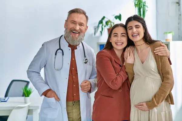 Cheerful lgbt couple expecting their baby standing near their grey bearded doctor, ivf concept — Stock Photo