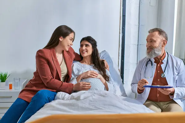 Joyful lgbt couple hugging looking at each other at medical check, in vitro fertilization concept — Stock Photo