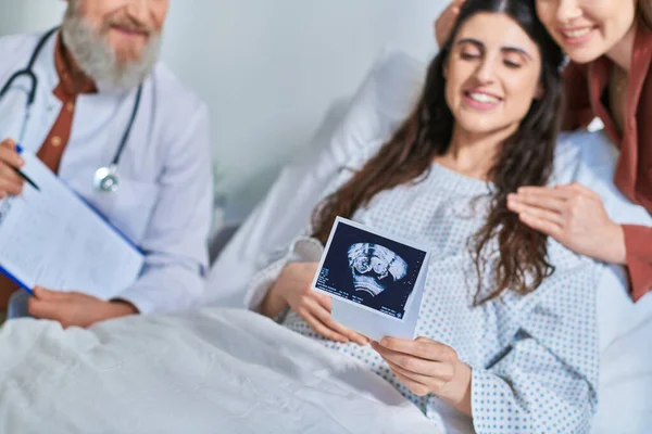 Cropped view of happy lesbian couple looking at ultrasound with doctor next to them, ivf concept — Stock Photo