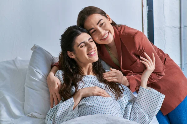 Alegre casal lgbt abraçando calorosamente e sorrindo com os olhos fechados, conceito de fertilização in vitro — Fotografia de Stock