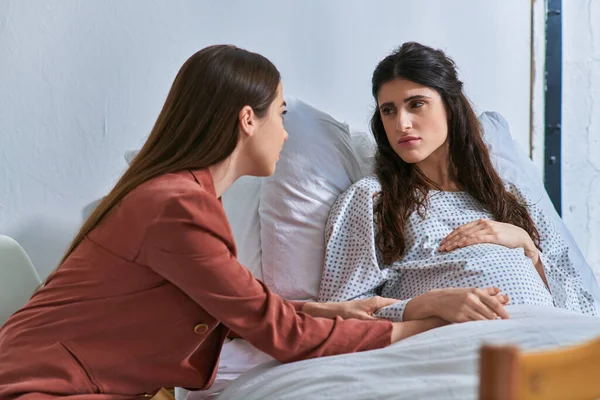 Young lgbt couple at hospital looking at each other holding hands, in vitro fertilization concept — Stock Photo