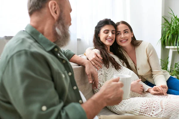 Happy lgbt couple sitting on sofa and hugging, grey bearded man looking at his daughter, ivf concept — Stock Photo