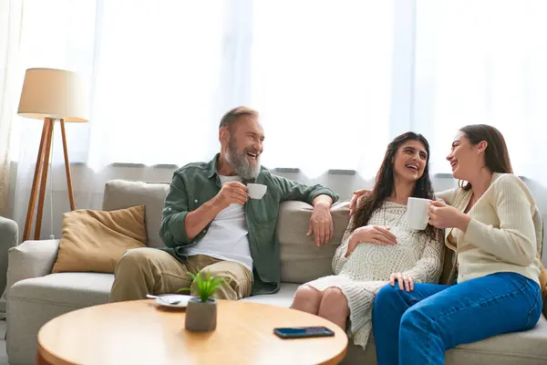 Famiglia e padre lgbt seduti sul divano ridendo e bevendo tè, concetto di fecondazione in vitro — Foto stock