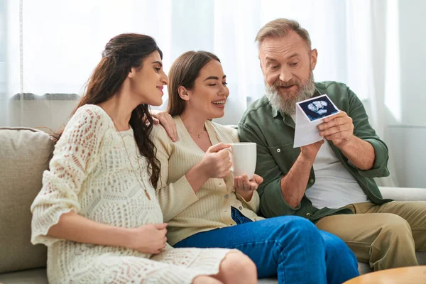 Happy father holding ultrasound of baby of his daughter showing it to her partner, ivf concept — Stock Photo