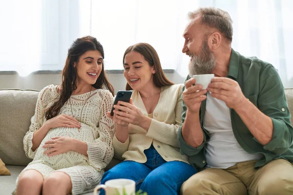 Graubärtiger Vater, der ihre Tochter ansieht, während sie auf das Telefon ihres Partners schaut, ivf concept — Stockfoto