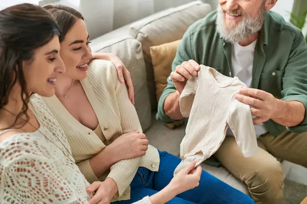 Cheerful lesbian couple looking at singlet that brought father of one of them, ivf concept — Stock Photo