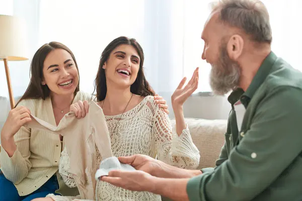 Father showing beanie and singlet to his pregnant daughter and her cheerful partner, ivf concept — Stock Photo