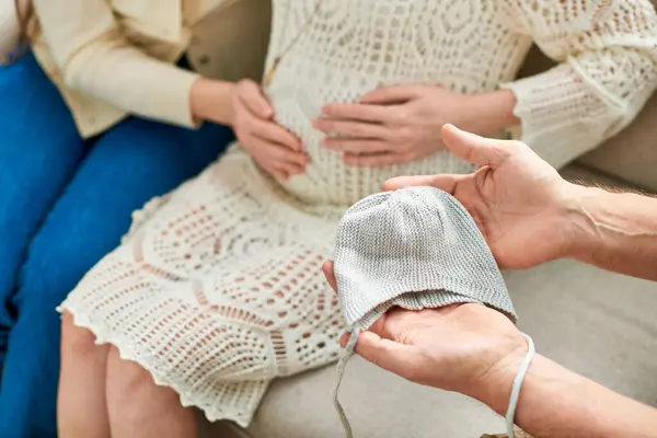 Cropped view of father showing beanie to his pregnant daughter and her partner, ivf concept — Stock Photo